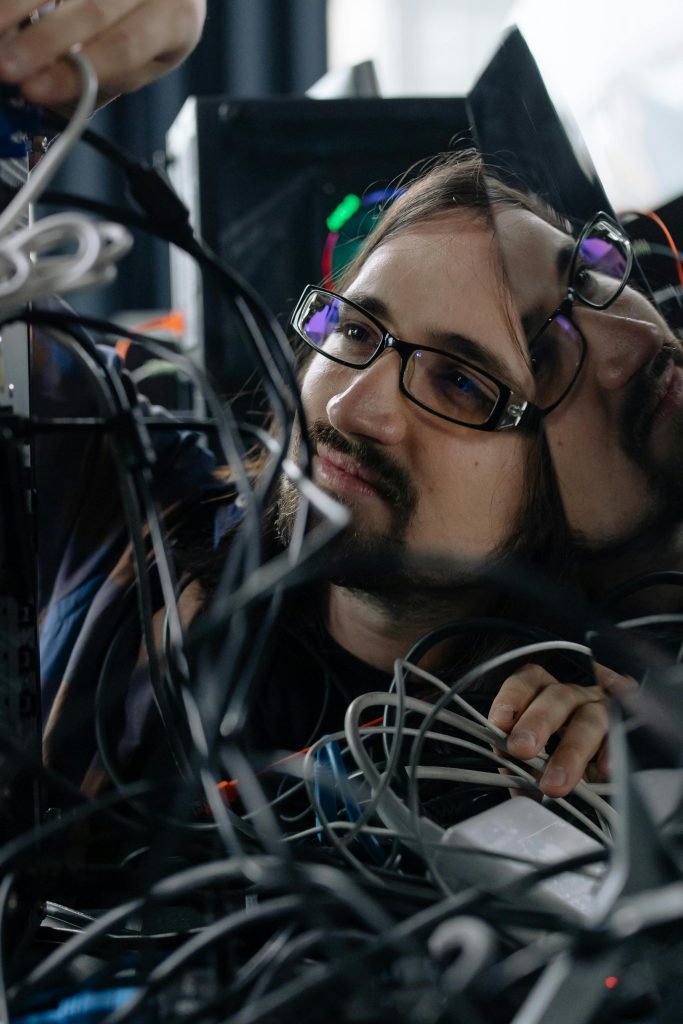 A focused male system administrator adjusting tangled network cables indoors.